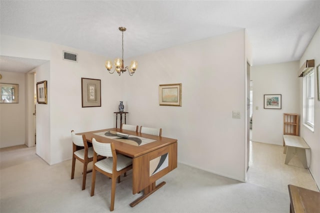 dining space featuring a textured ceiling, a chandelier, and light colored carpet