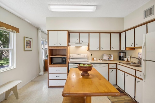 kitchen with white appliances, sink, white cabinets, and a textured ceiling