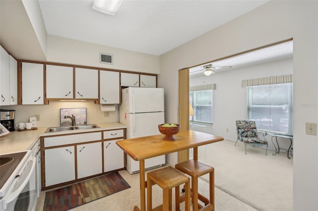 kitchen featuring white cabinets, white appliances, light carpet, sink, and ceiling fan