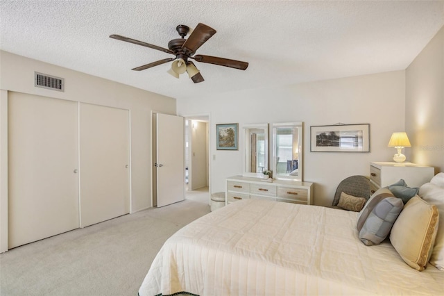 bedroom with a textured ceiling, light colored carpet, and ceiling fan