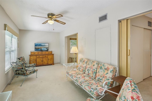 carpeted living room featuring a textured ceiling and ceiling fan