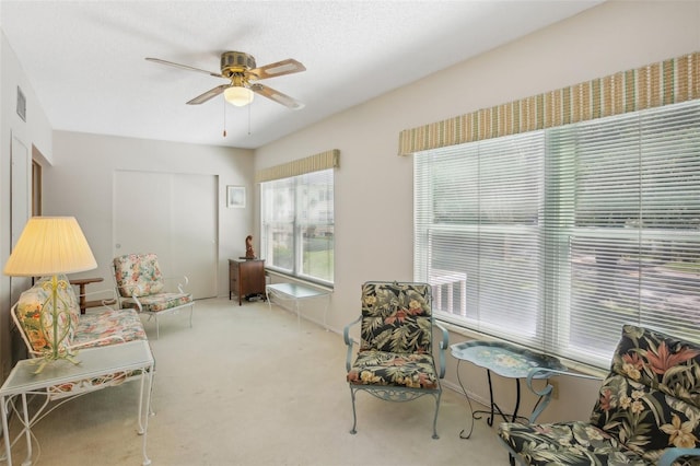 sitting room featuring a textured ceiling, ceiling fan, and carpet flooring