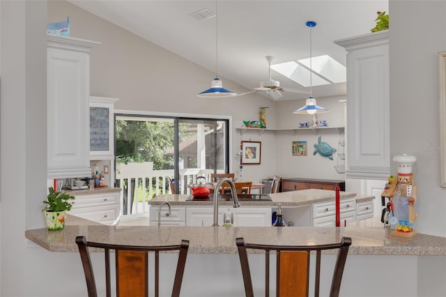 kitchen featuring white cabinetry, pendant lighting, vaulted ceiling with skylight, and ceiling fan