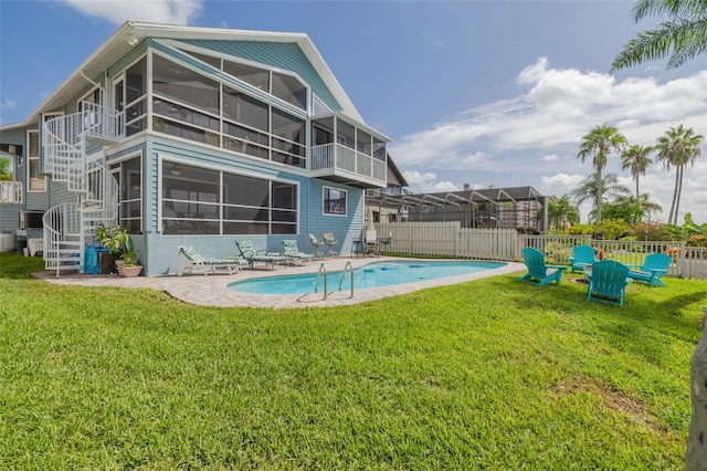 view of pool featuring a yard, a patio area, and a sunroom