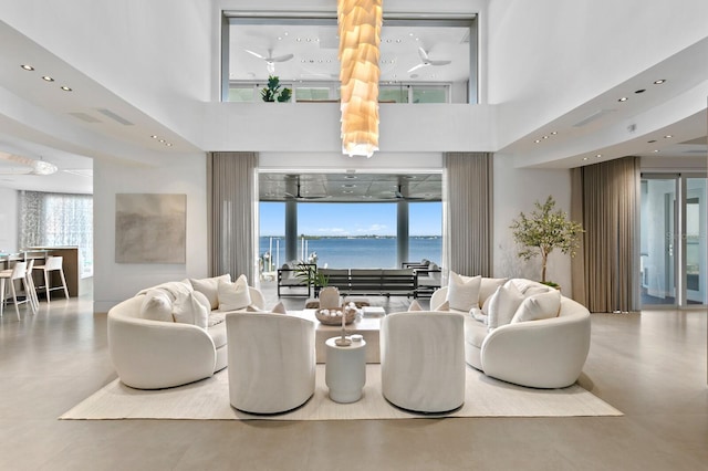 living room with a high ceiling, a water view, and concrete flooring