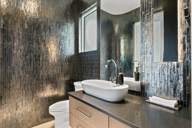 bathroom featuring tile walls, vanity, and toilet