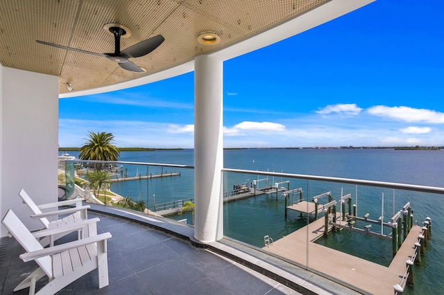 balcony with ceiling fan, a boat dock, and a water view