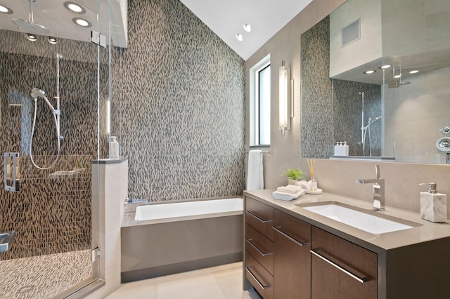 bathroom featuring tile patterned flooring, vaulted ceiling, separate shower and tub, and vanity