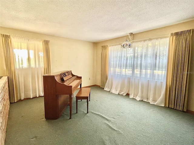 sitting room featuring a textured ceiling, carpet floors, and an inviting chandelier