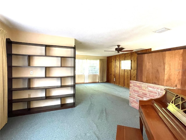 unfurnished living room with ceiling fan, carpet flooring, and wooden walls