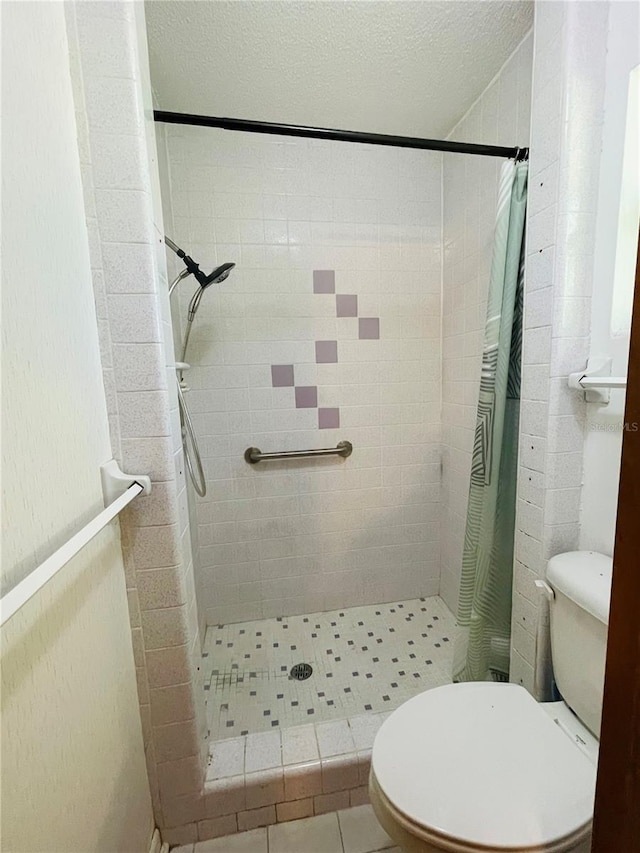 bathroom featuring toilet, a textured ceiling, and a shower with curtain