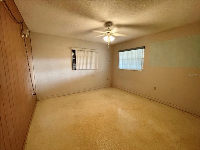 unfurnished room with wooden walls, a textured ceiling, and ceiling fan