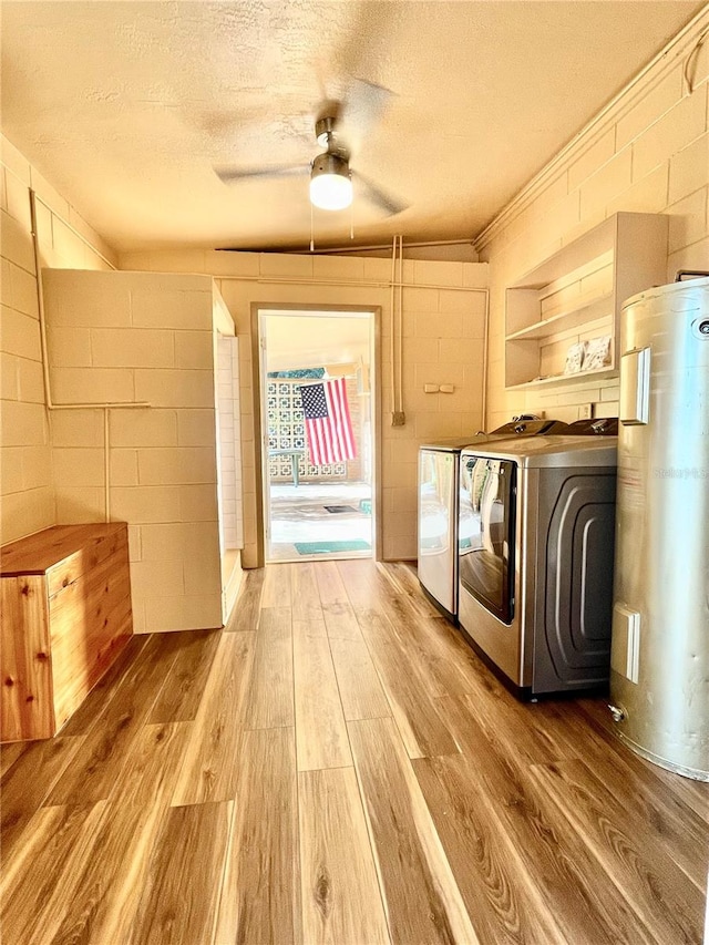 washroom with water heater, washing machine and clothes dryer, hardwood / wood-style flooring, and a textured ceiling