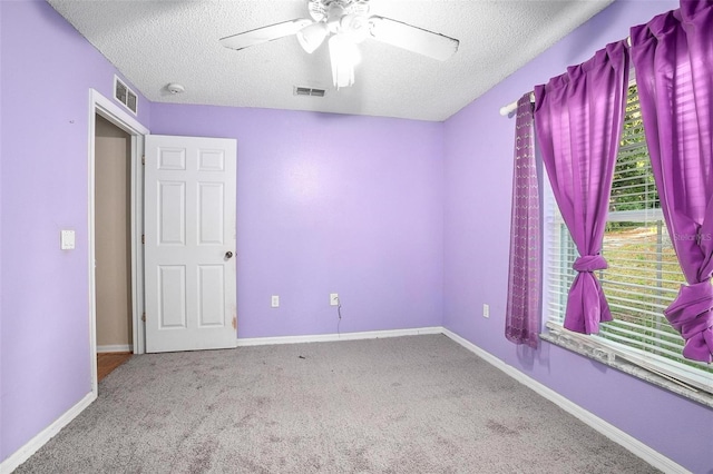 spare room featuring carpet, ceiling fan, and a textured ceiling