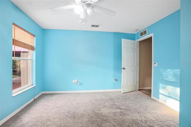 spare room featuring ceiling fan, carpet, and a textured ceiling