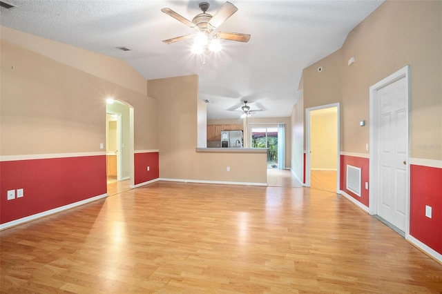 empty room featuring lofted ceiling, ceiling fan, light hardwood / wood-style floors, and a textured ceiling