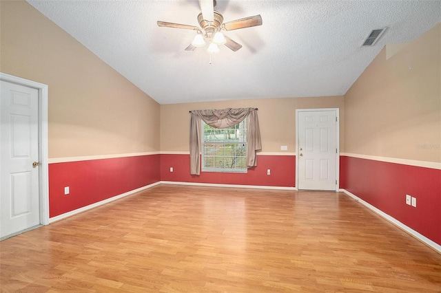 spare room with hardwood / wood-style floors, lofted ceiling, ceiling fan, and a textured ceiling