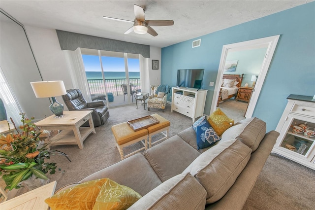 living room featuring light colored carpet, ceiling fan, and a water view