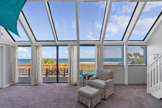 sunroom featuring a view of the beach, lofted ceiling, a healthy amount of sunlight, and a water view