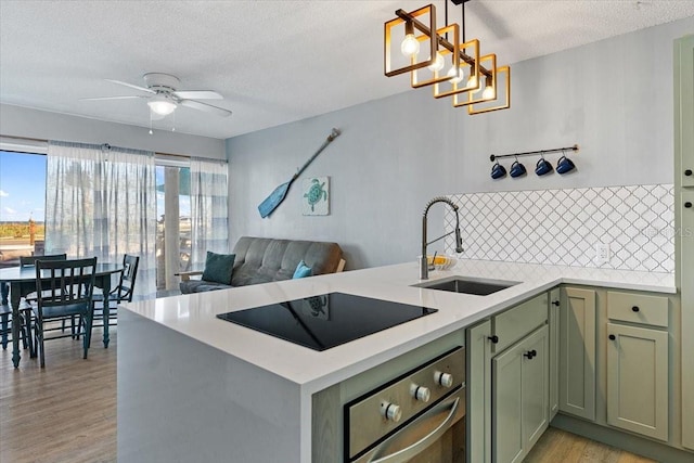 kitchen with pendant lighting, stainless steel oven, light hardwood / wood-style flooring, black electric stovetop, and sink