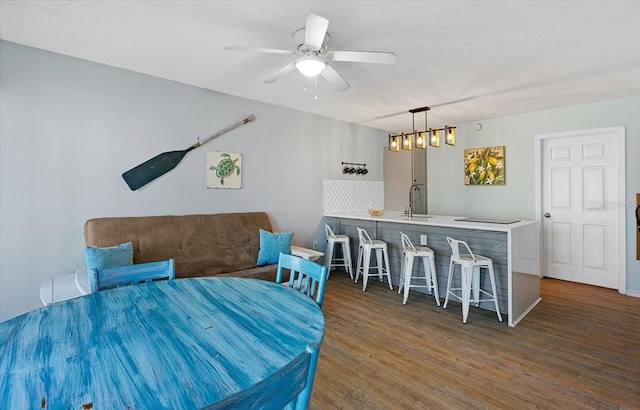 dining area featuring a textured ceiling, ceiling fan, dark wood-type flooring, and sink