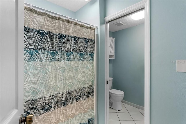 bathroom featuring toilet, tile floors, and a textured ceiling