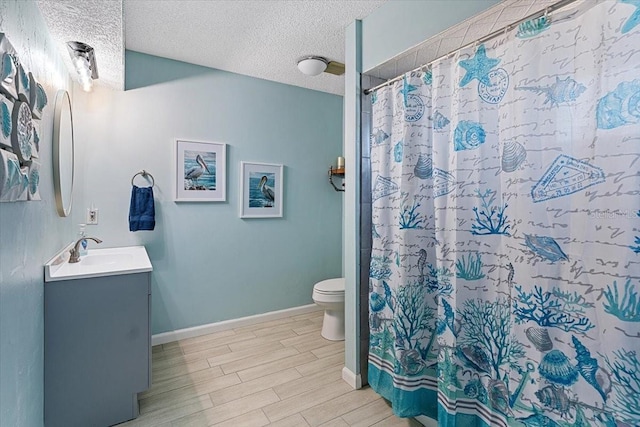 bathroom featuring toilet, a textured ceiling, and vanity