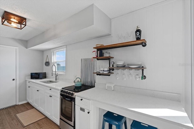 kitchen with sink, electric range, white cabinets, dark wood-type flooring, and a textured ceiling