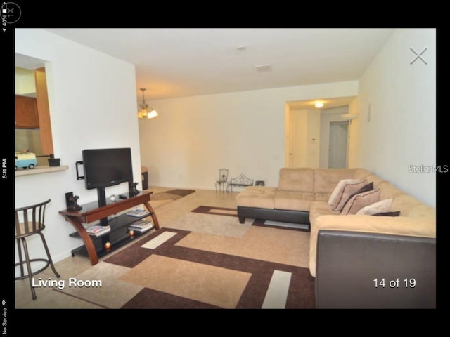 living room featuring light colored carpet and an inviting chandelier