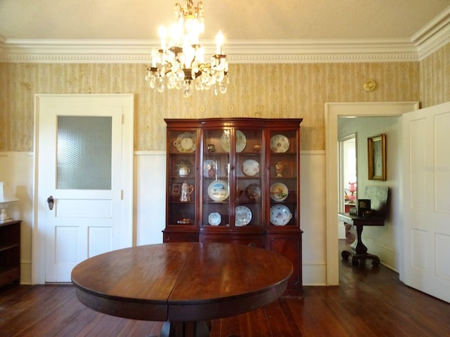 dining space with dark wood-type flooring, ornamental molding, and a notable chandelier