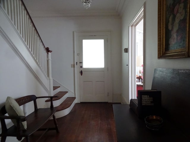 foyer entrance featuring a chandelier, ornamental molding, and dark hardwood / wood-style floors