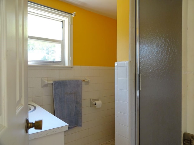 bathroom with tile walls, vanity, and a shower with shower door