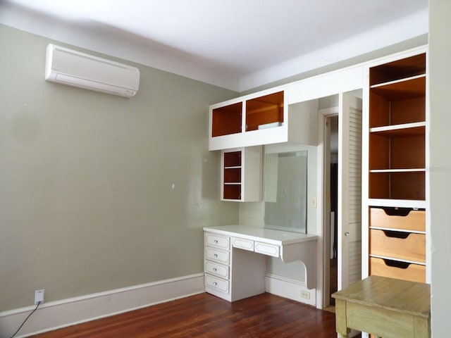 interior space featuring built in desk, a wall mounted air conditioner, and dark hardwood / wood-style flooring