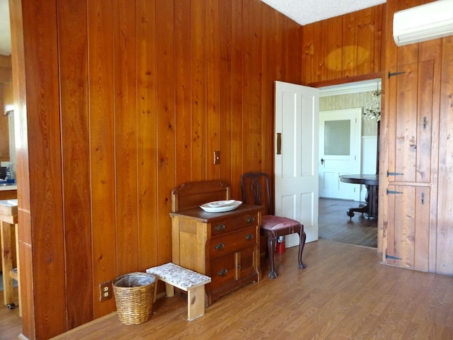 miscellaneous room with wooden walls, a wall mounted AC, and hardwood / wood-style flooring