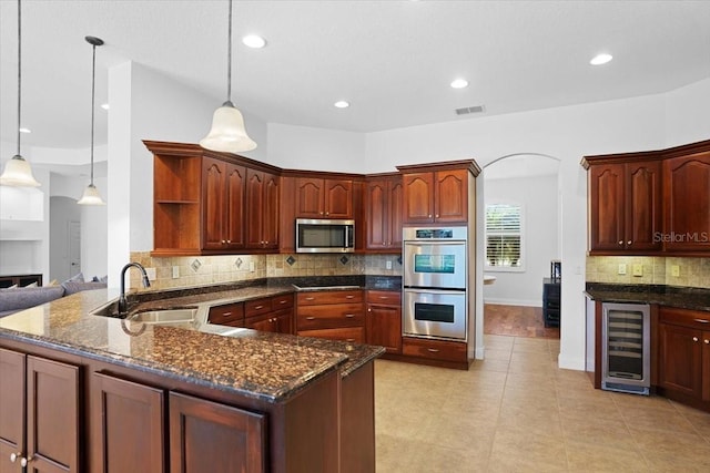 kitchen featuring stainless steel appliances, light tile floors, wine cooler, backsplash, and hanging light fixtures