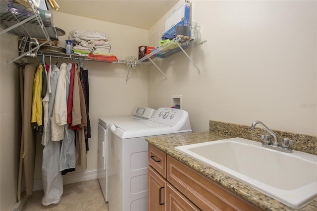 clothes washing area with washer and clothes dryer, cabinets, and sink