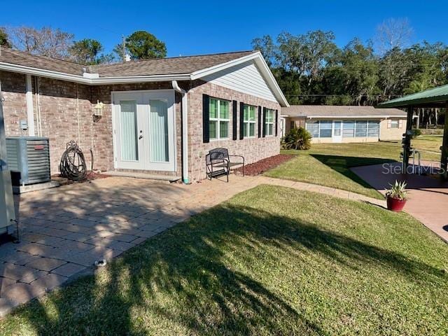 back of house featuring a lawn, central AC unit, french doors, and a patio area