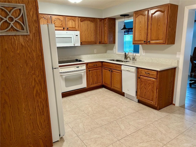 kitchen featuring pendant lighting, sink, white appliances, and light tile patterned floors