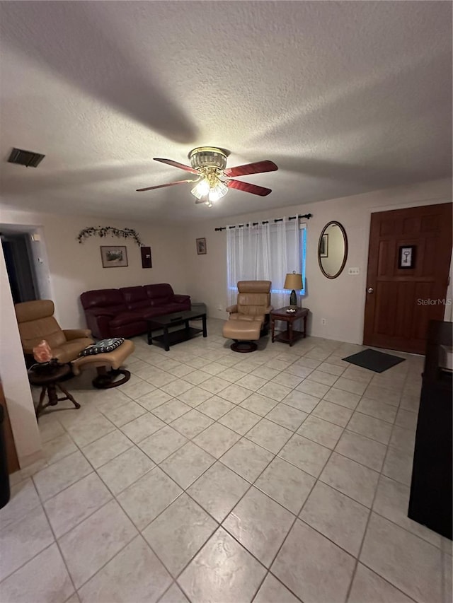 living room with a textured ceiling, light tile patterned floors, and ceiling fan