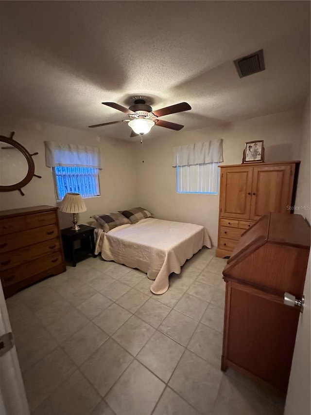 bedroom featuring a textured ceiling, light tile patterned floors, and ceiling fan