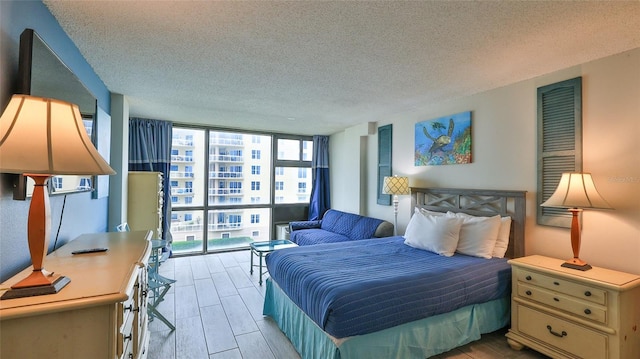 bedroom with a textured ceiling, a wall of windows, and wood tiled floor