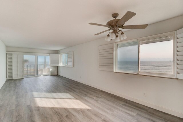 spare room featuring ceiling fan, light hardwood / wood-style floors, and a water view