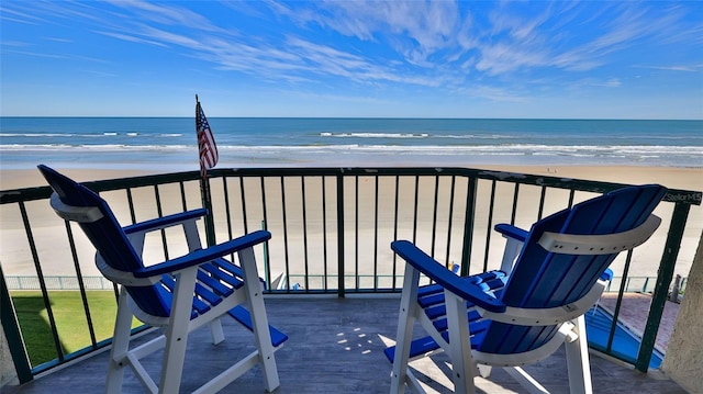 balcony with a water view and a view of the beach