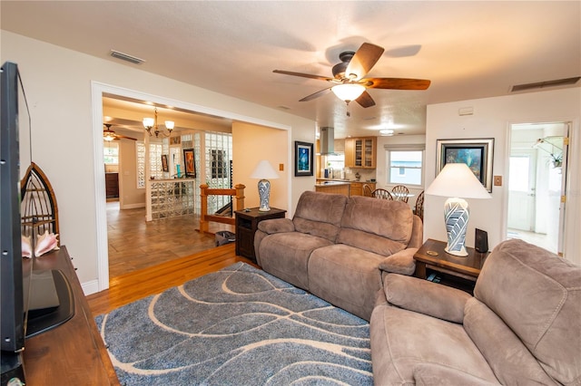 living room with a healthy amount of sunlight, wood-type flooring, and ceiling fan with notable chandelier