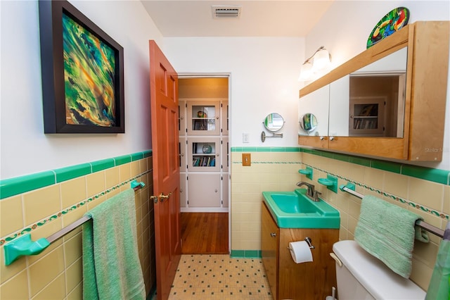 bathroom featuring vanity, tasteful backsplash, toilet, and tile walls