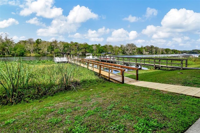 view of dock with a water view and a lawn