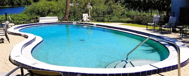 pool with a patio area and fence