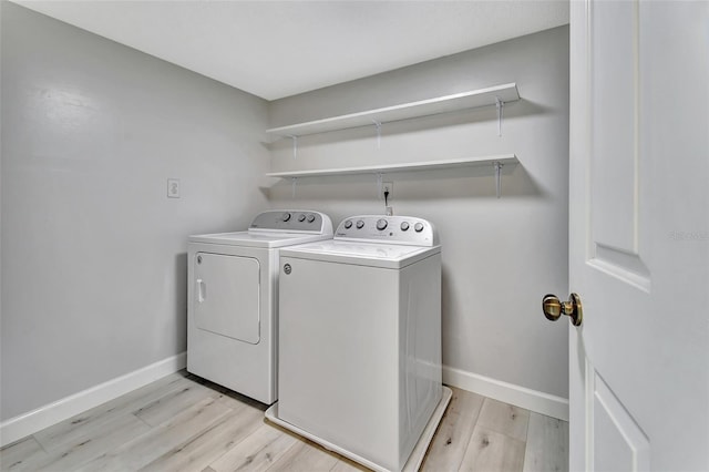 clothes washing area featuring laundry area, washer and clothes dryer, light wood-type flooring, and baseboards