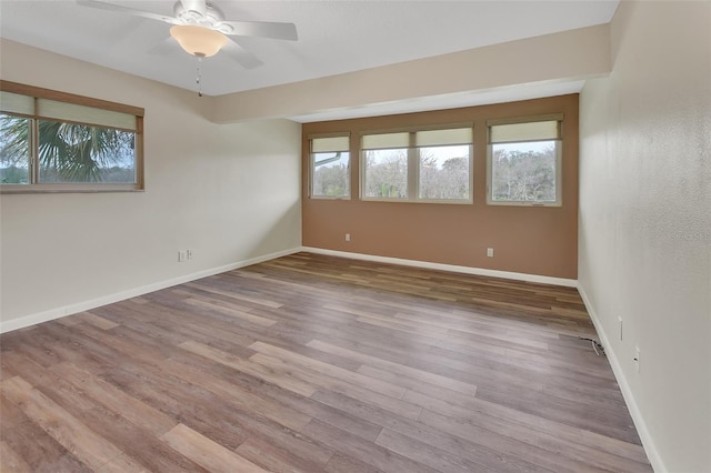 spare room with ceiling fan, wood finished floors, and baseboards