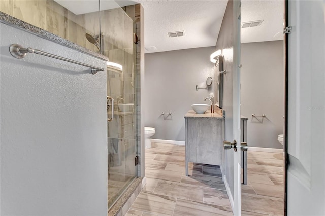 bathroom featuring toilet, a stall shower, visible vents, and a textured ceiling